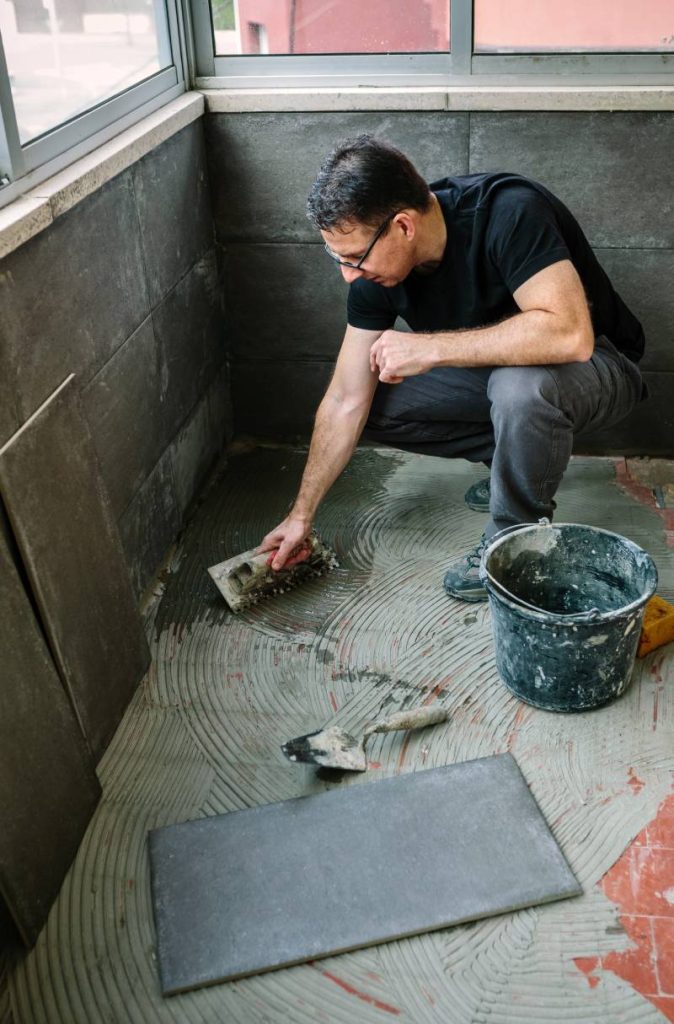 Workman laying a new tile floor on a terrace