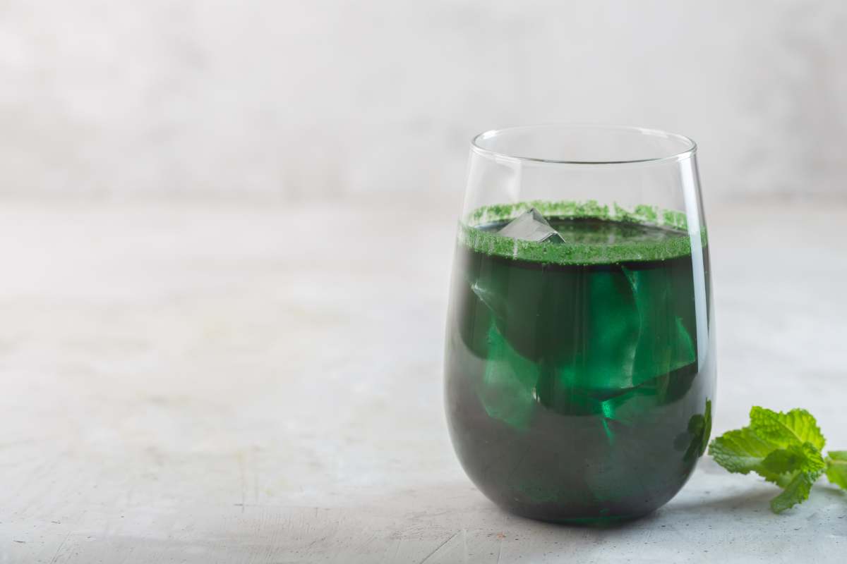 Green drink prepared with single celled green algae chlorella. Detox superfood in the glass on the gray background