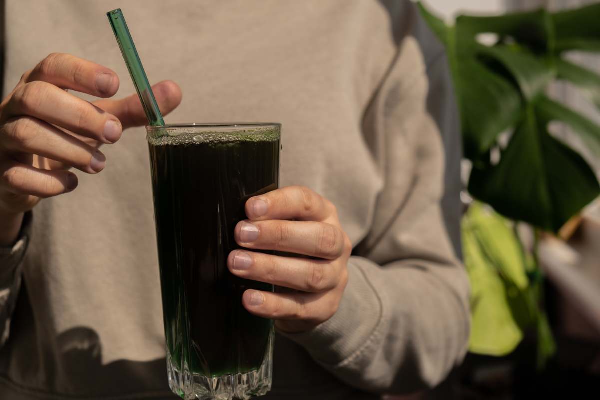 Unrecognizable woman drinking Natural organic green spirulina algae powder drink on neutral beige background. Chlorella seaweed vegan superfood cocktails smoothie supplement source and detox drinking. Innovative ingredient functional environmentally friendly food. Copy space Healthy nutritional antioxidant concept.