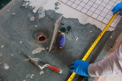 Plaster repair work laying tile, trowel in a man worker using measuring and marking