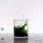 A green iced cocktail splash on the table on a white background