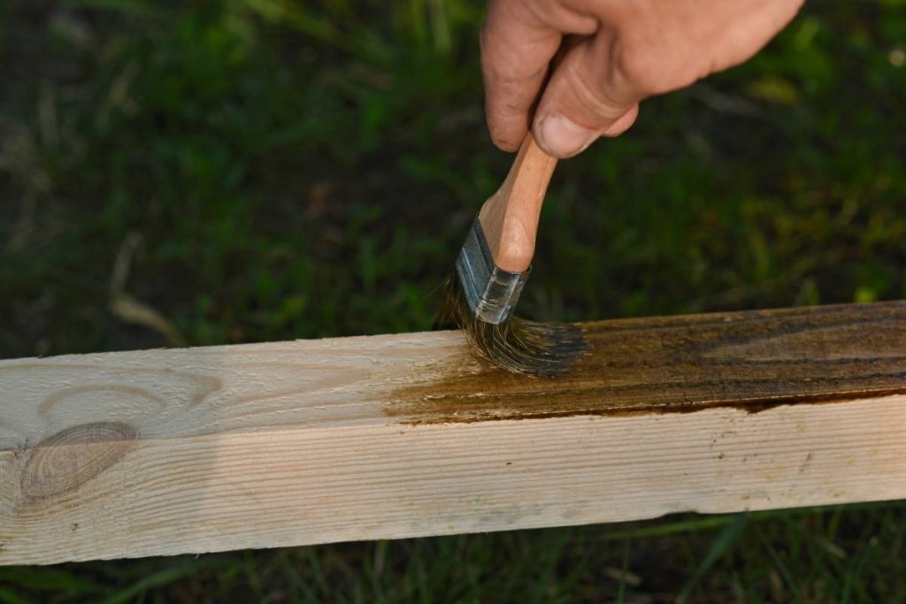 Applying chemical deck stripper to break down old timber coatings